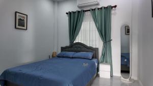 a bedroom with a blue bed with green curtains at บ้านพักขอนแก่น888 in Ban Non Muang