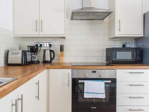 a kitchen with white cabinets and a stove with a microwave at Shirehampton Apartment in Shirehampton