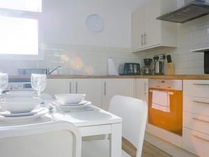 a white kitchen with a white table and chairs at Shirehampton Apartment in Shirehampton +5 photos