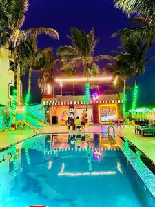 a swimming pool in front of a building with palm trees at Hotel Sapphire International in Puri