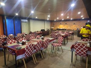 a dining room with tables and chairs with people in the background at Hotel Sapphire International in Puri