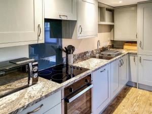 a kitchen with white cabinets and a stove top oven at Oakbank Cottage - Uk7574 in Pitlochry