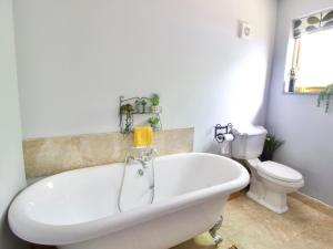 a white bath tub in a bathroom with a toilet at The Stable At Hilltop Farm in Mottisfont +5 photos