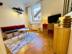 a living room with a red couch and a television at L'escale Annécienne in Annecy