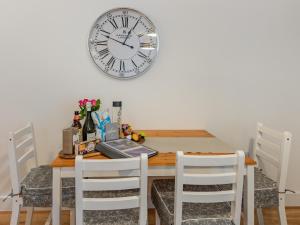 a dining room table with a clock on the wall at Lilypad in Ringwood