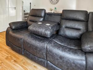 a leather couch with a foot stool on top of it at Lilypad in Ringwood