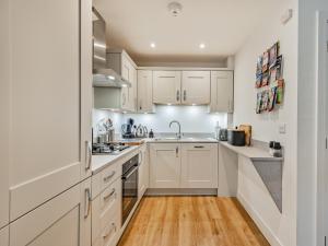 a kitchen with white cabinets and a wooden floor at Lilypad in Ringwood +16 photos