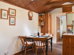 a kitchen with a table with chairs and a clock on the wall at The Stables in Winfrith Newburgh