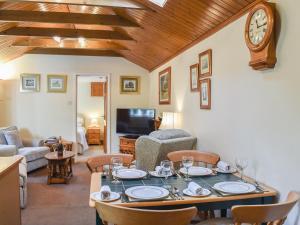 a living room with a table and a clock on the wall at The Stables in Winfrith Newburgh