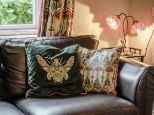 a leather couch with two pillows on it at Jasmine Cottage - Uk35245 in Llanfyrnach