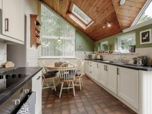 a kitchen with white cabinets and a wooden ceiling at Jasmine Cottage - Uk35245 in Llanfyrnach