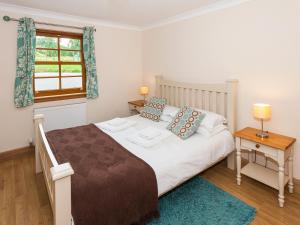a bedroom with a large bed and a window at Honeysuckle Cottage - Ukc6255 in Linlithgow