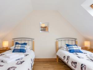 two beds in a room with white walls and blue pillows at Honeysuckle Cottage - Ukc6255 in Linlithgow