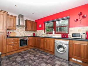a kitchen with red walls and a washing machine at Larrach Beag-Ukc5059 in Aviemore