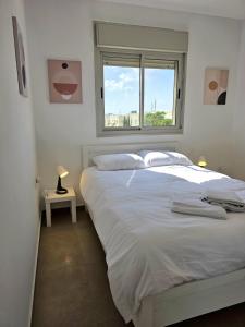 a bedroom with a large white bed with a window at Your home in Pardes Hanna in Pardes H̱anna