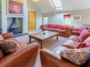 a living room with couches and a table and a fireplace at The Coach House - Uk35246 in Llanfyrnach