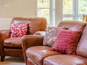 a brown leather couch with colorful pillows on it at The Coach House - Uk35246 in Llanfyrnach +26 photos