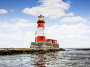 a red and white lighthouse on the water at Lindisfarne Cottage -Ukc5295 in Beadnell