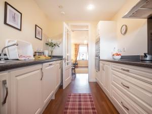 a kitchen with white cabinets and black counter tops at Dalfaber View-Ukc5054 in Aviemore