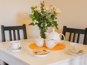 a table with two cups and a vase with flowers at Dalfaber View-Ukc5054 in Aviemore +7 photos