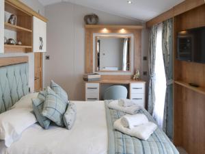 a bedroom with a bed and a desk and a mirror at Herdwick Lodge - Uk3426 in Newton on the Moor +5 photos