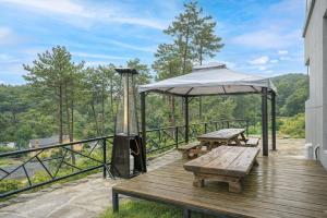 a wooden deck with two benches and an umbrella at Busan Mandiga Pool Villa in Busan