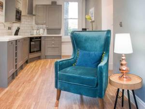 a blue chair in a kitchen with a table and a lamp at Broad Street in Bath