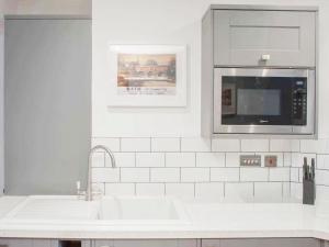 a white kitchen with a sink and a microwave at Broad Street in Bath +16 photos