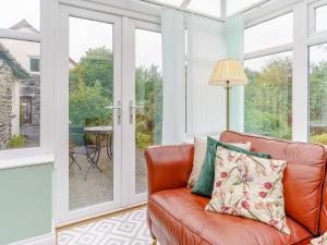 a living room with a leather couch and windows at Ivy Cottage - Uk35243 in Llanfyrnach
