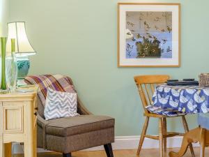 a chair sitting next to a table with a picture on the wall at Ivy Cottage - Uk35243 in Llanfyrnach