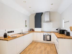 a kitchen with white cabinets and wooden floors at 1 Monkbar Mews - Uk2690 in York