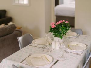 a table with plates and glasses and a vase with pink flowers at Corner Cottage - Ukc4962 in Tawstock