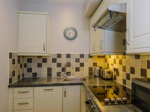 a kitchen with a sink and a clock on the wall at Corner Cottage - Ukc4962 in Tawstock