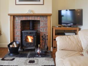 a living room with a brick fireplace and a television at Bevan House in Llansaintfraed in Elvel