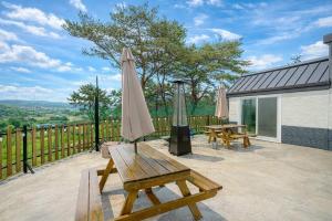 a patio with two benches and an umbrella at Busan Mandiga Pool Villa in Busan