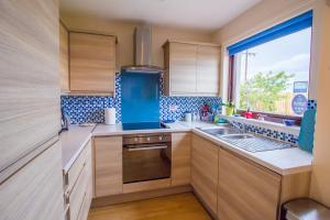 cocina con armarios de madera, fregadero y ventana en Beach House Walk - Crail - Home from Home, en Crail