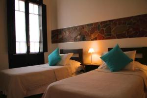 a hotel room with two beds and a window at Posada El Capullo in Colonia del Sacramento