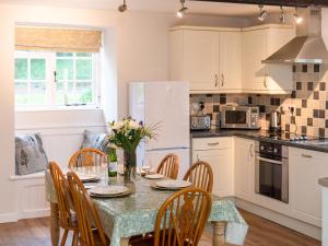 a kitchen with a table and chairs and a kitchen with white cabinets at Number Eight - Ukc4971 in Tawstock +19 photos