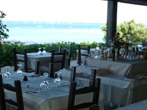 a table with white tables and chairs with a view of the ocean at Residence Hotel La Pelosetta in Stintino