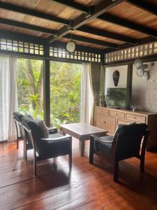 a living room with a table and chairs and a tv at Mi Casa - The gem of Ijen in Banyuwangi