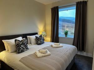 a bedroom with a large bed with pillows and a window at Auch - Cottages in Bridge of Orchy