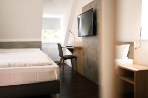a bedroom with a bed and a desk with a television at Hotel Stadt Kamen in Kamen