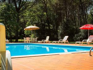 una piscina con sillas de césped, sombrillas y sillas en Belvilla by OYO Holiday Home with Pool, en Canneto