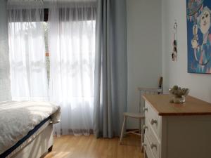 a bedroom with a bed and a window with curtains at Sea Urchin in Gordonʼs Bay