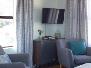 a living room with two chairs and a flat screen tv at Sea Urchin in Gordonʼs Bay