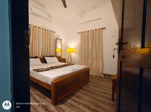 a bedroom with a bed with white sheets and curtains at Sandy Steps in Varkala