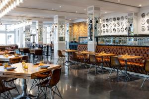 a restaurant with wooden tables and chairs and a bar at Kimpton - Pittman Hotel by IHG in Dallas
