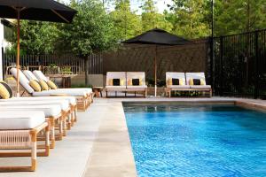 a pool with chaise lounge chairs and an umbrella at Kimpton - Pittman Hotel by IHG in Dallas