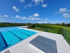 a large swimming pool with a view of a field at Eilantgeluk in Oudesluis