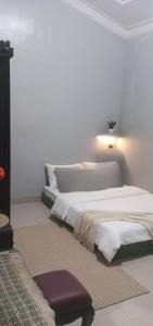 a white bedroom with two beds and a lamp at Adiyantum Homestay in Jetis